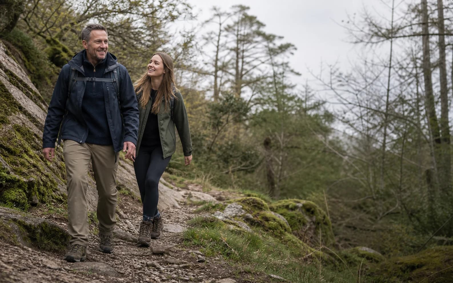 Man and daughter walking confidently on an uneven woodland trail