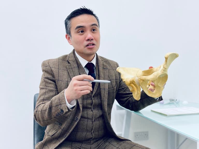 Professor Lee explaining joint anatomy with an anatomical model during a consultation